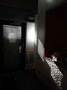 Sonnenstrahlen fallen durch die im Lockdown heruntergefahrenen Jalousien unserer Küche